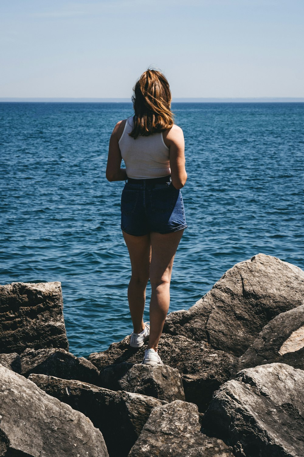 a woman standing on a rock looking out at the water