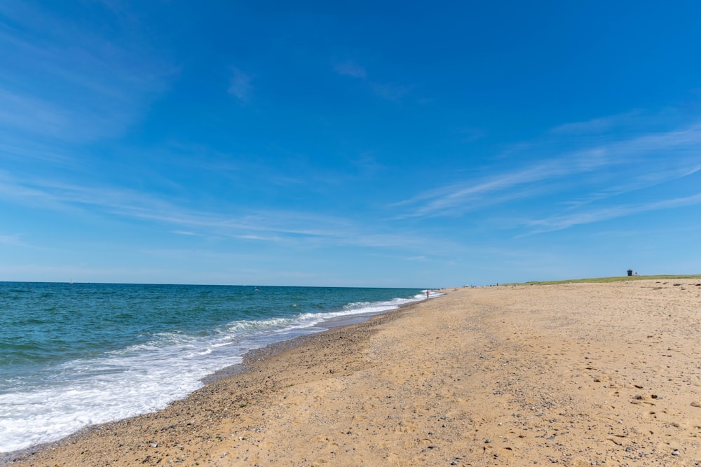 a sandy beach with blue sky and clouds