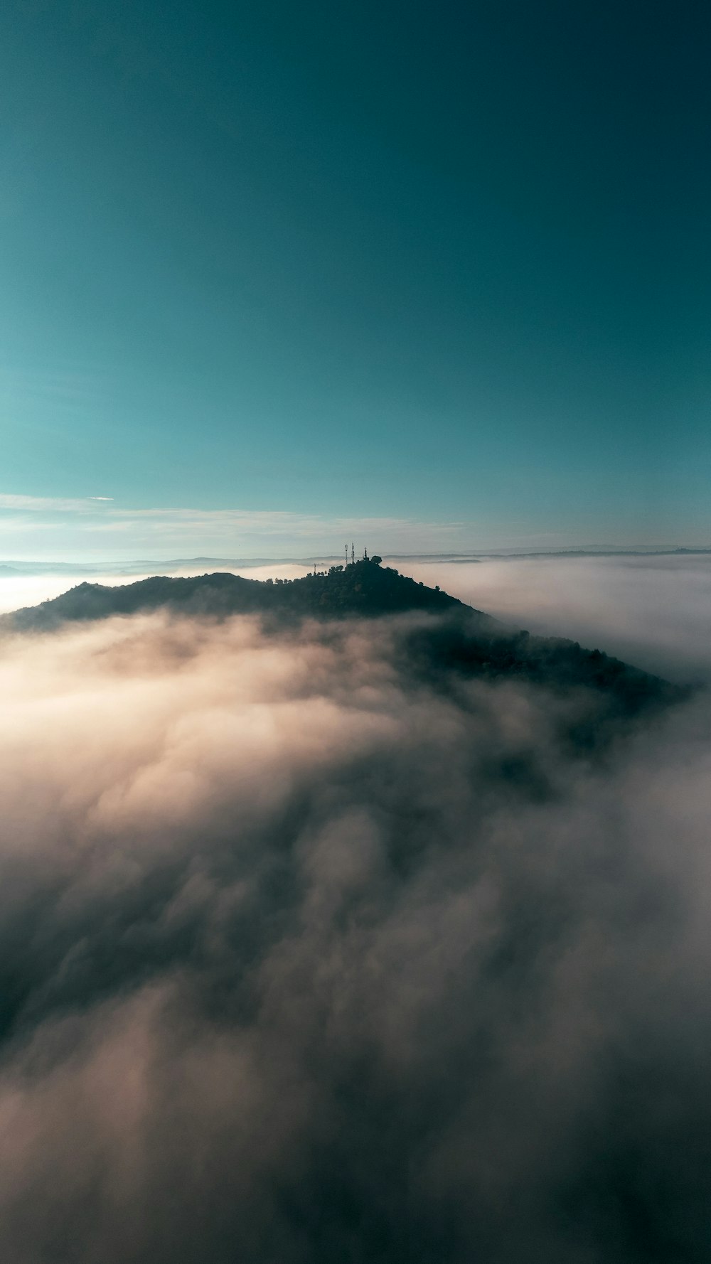 a view of a mountain with clouds below