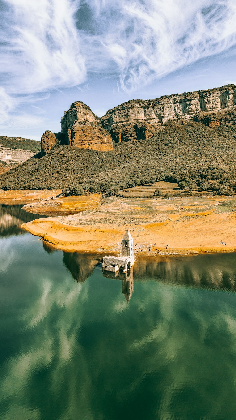 a body of water with a rocky cliff and a tower