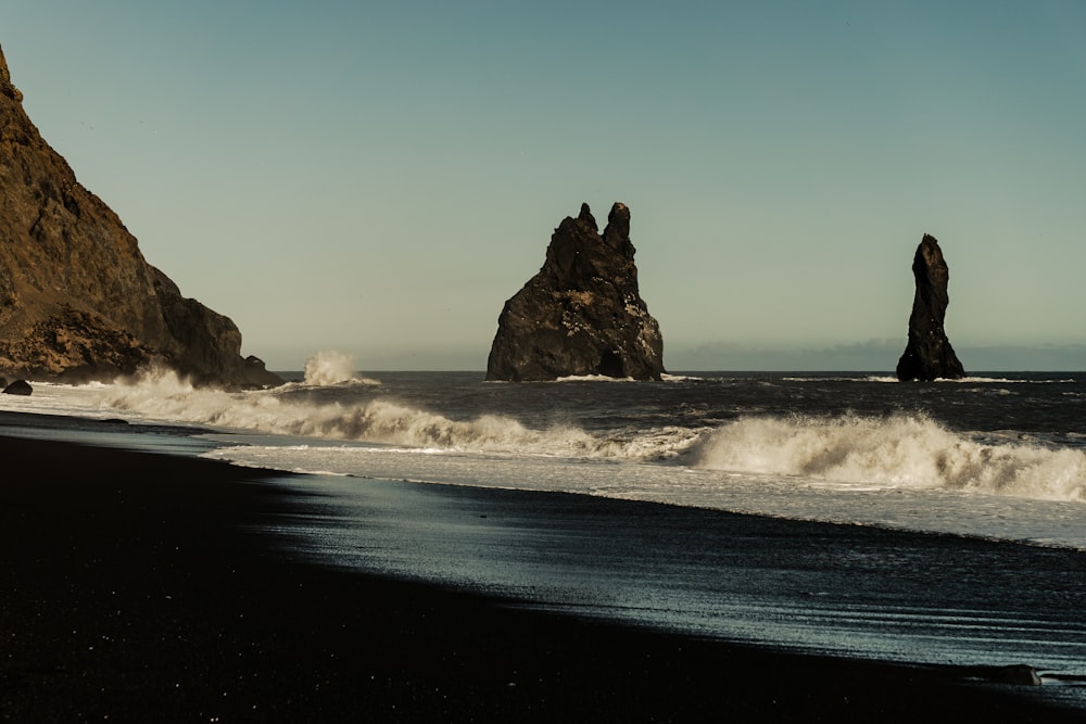 a beach with waves crashing against the rocks