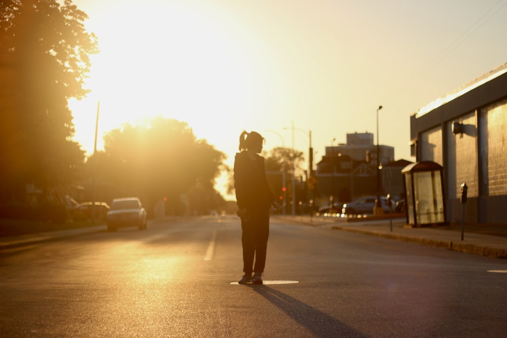 a person standing in the middle of a road with a building and trees