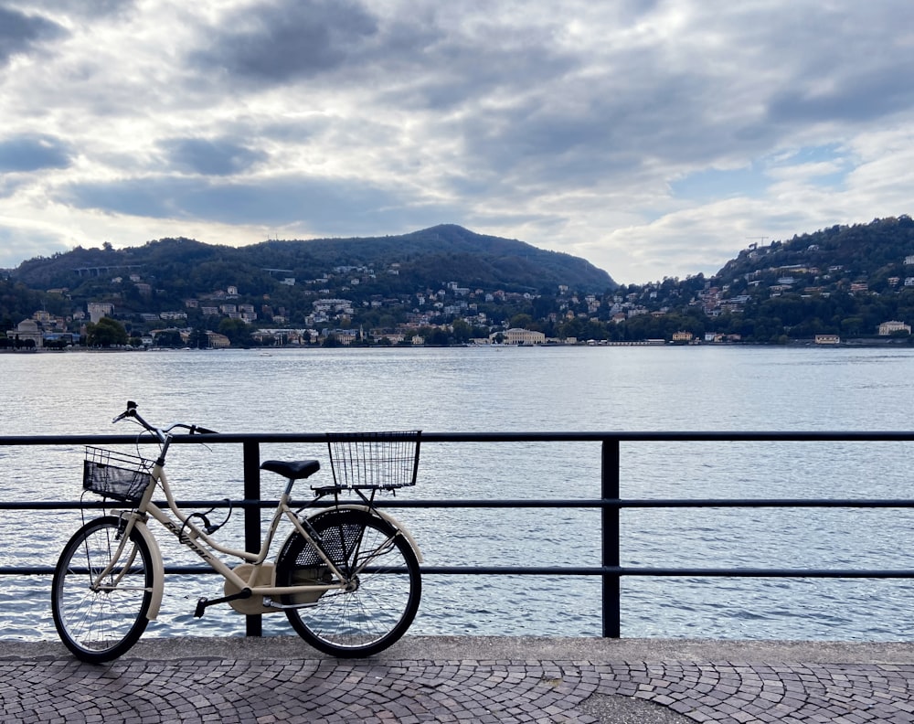 a bicycle parked on a railing by a body of water