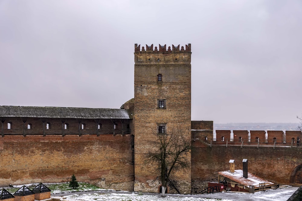 a stone tower with a brick wall and a tree in front of it