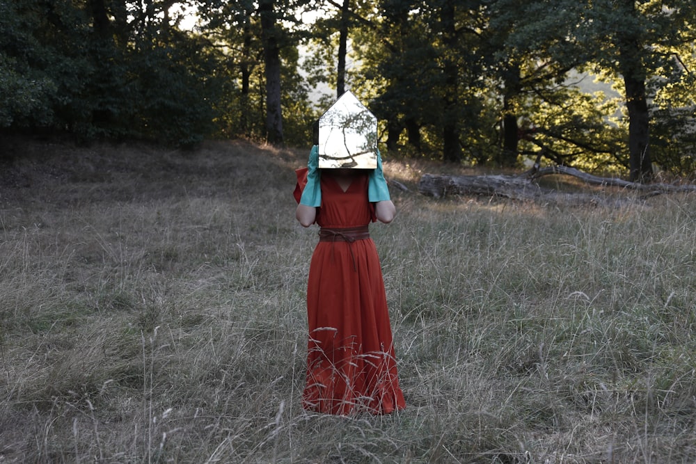 a person in a red dress in a field with trees in the background