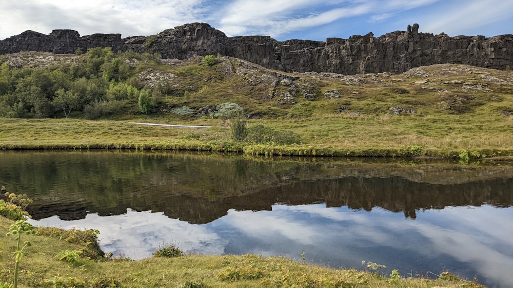 a lake with a rocky cliff in the background