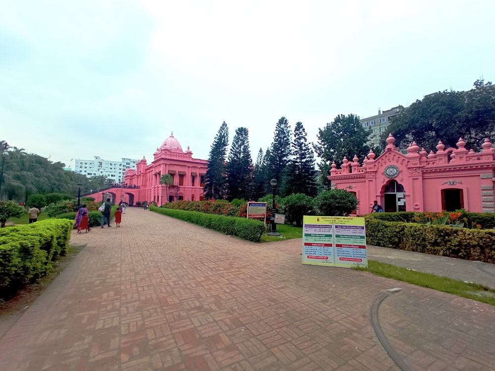 a brick walkway leading to a pink building with a sign in front