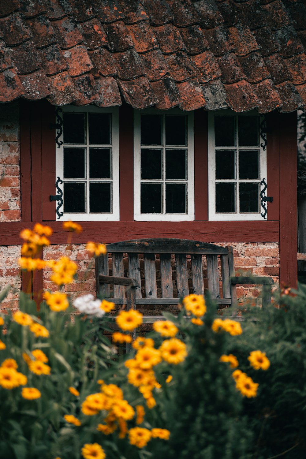 a house with a grass roof and flowers in front of it