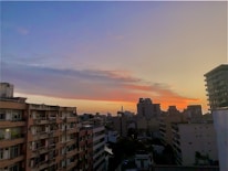 A sleek city skyline with various residential and commercial buildings at sunset.