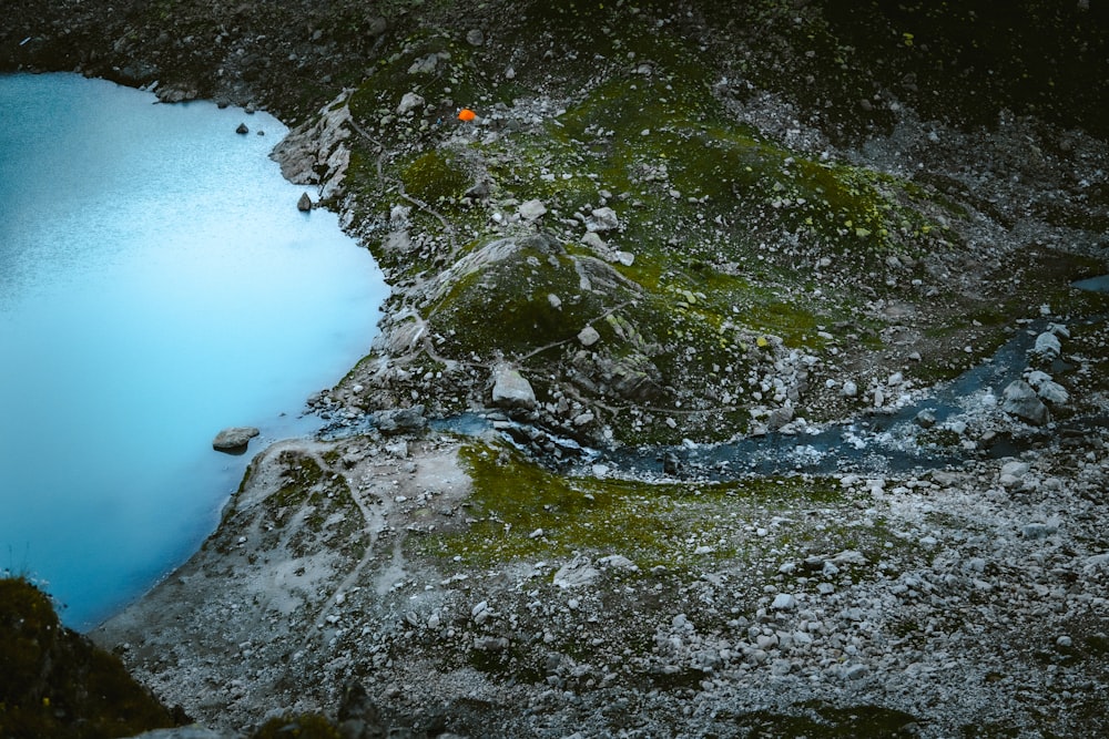 a rocky beach with a body of water in the background