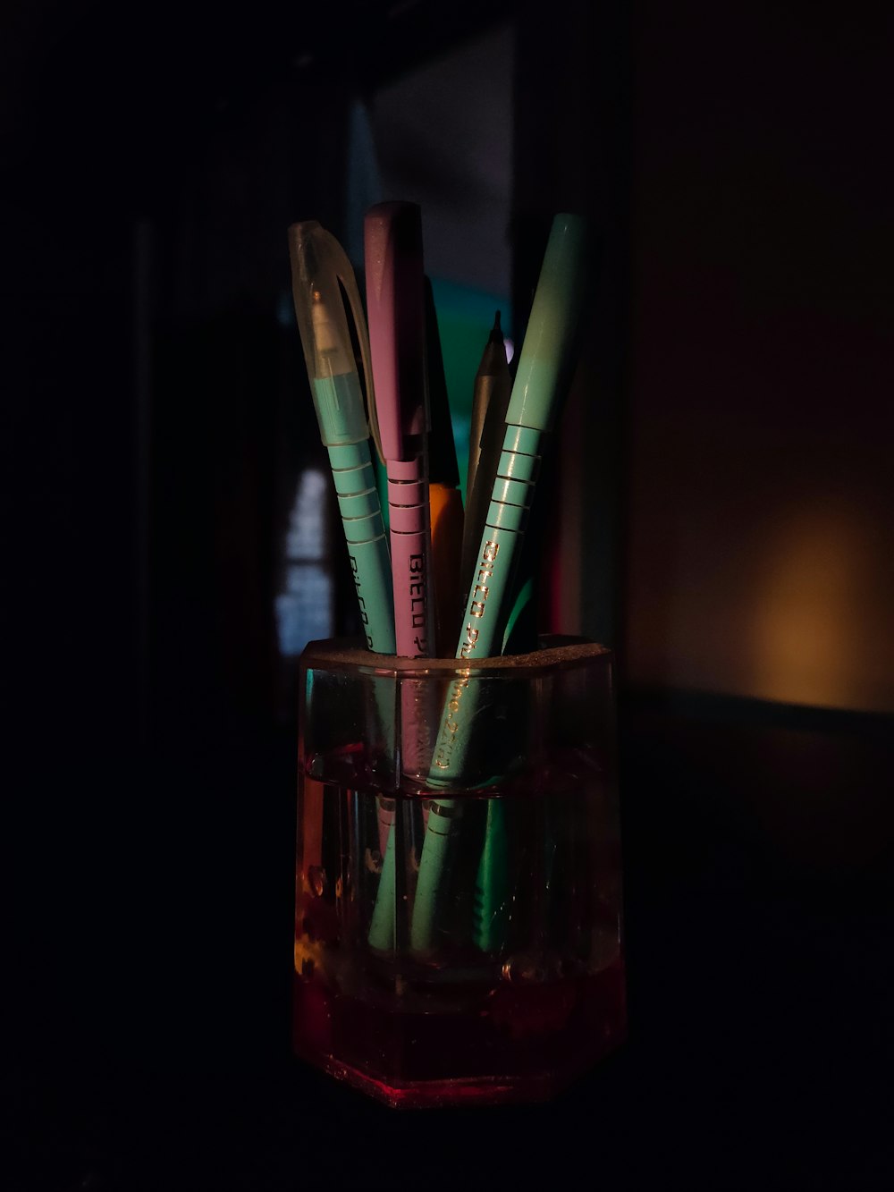 a glass with pens in it