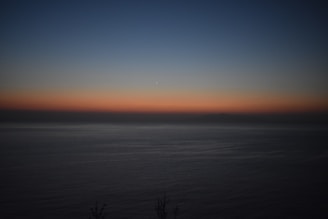 A horizontal translucent box glowing faintly against a background of a calm ocean at sunset.
