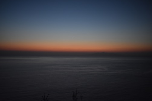 A horizontal translucent box glowing faintly against a background of a calm ocean at sunset.