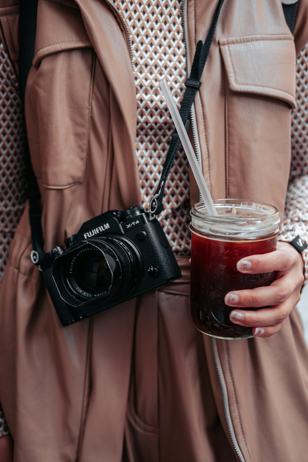 a person holding a camera and a glass of liquid