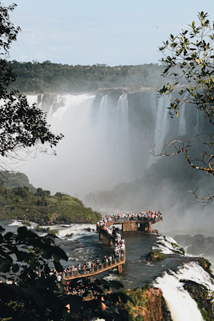 a bridge over a river with a waterfall and trees