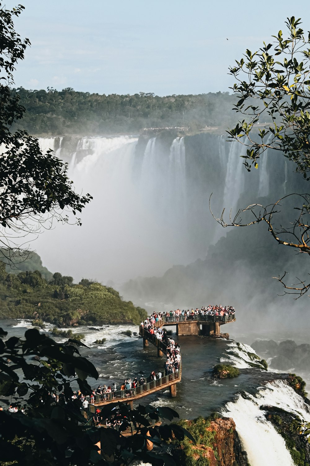 Eine Brücke über einen Fluss mit einem Wasserfall und Bäumen