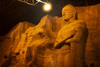 Ancient Buddha statue carved into a rock face at one of Swat's archaeological sites, bathed in soft sunlight.