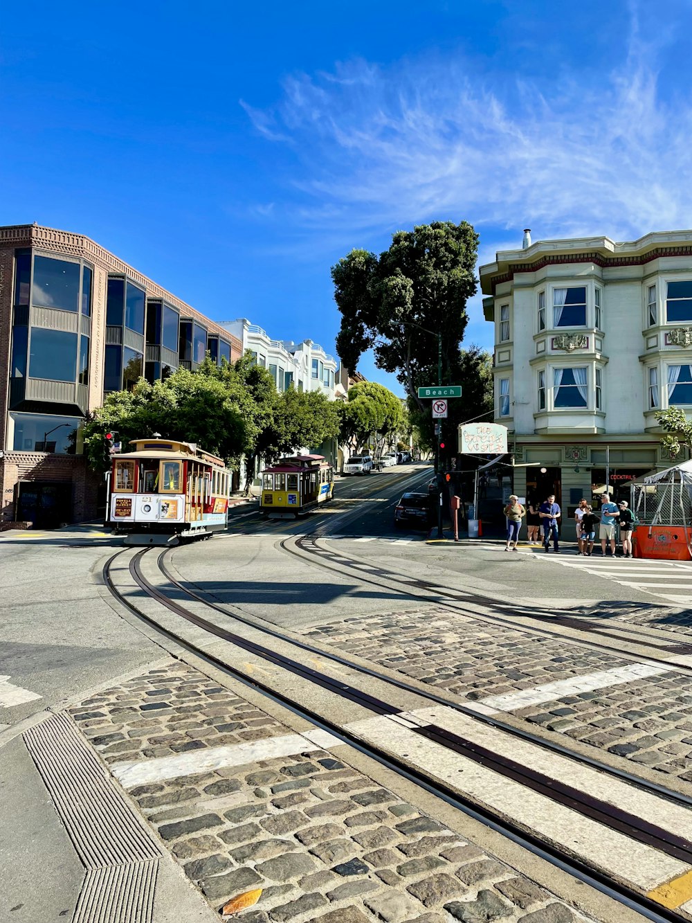 a couple of trolleys on a street with buildings and trees