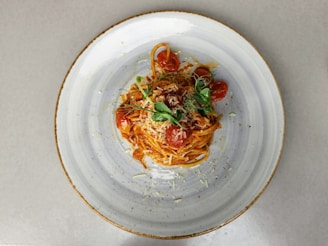A steaming plate of spaghetti with rich tomato sauce and fresh basil leaves, captured in warm natural light.
