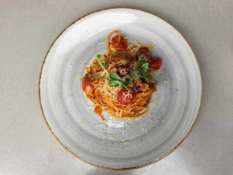 A steaming plate of spaghetti with rich tomato sauce and fresh basil leaves, captured in warm natural light.