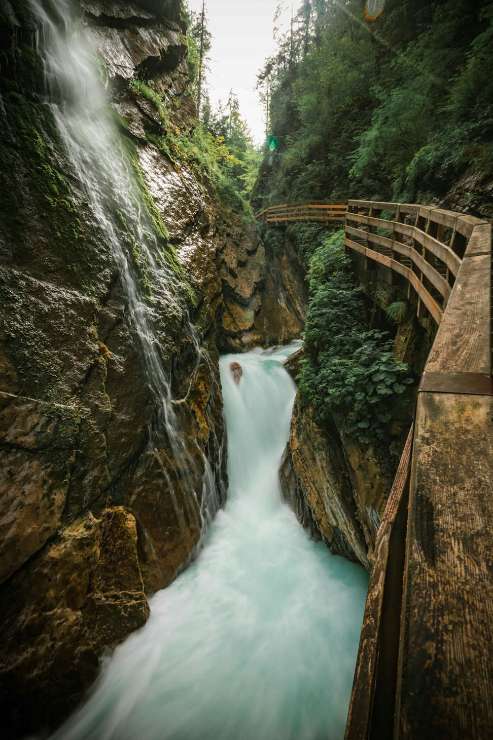 a waterfall with a bridge and trees