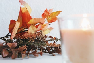 a plant with orange leaves, fall garland and scented candle