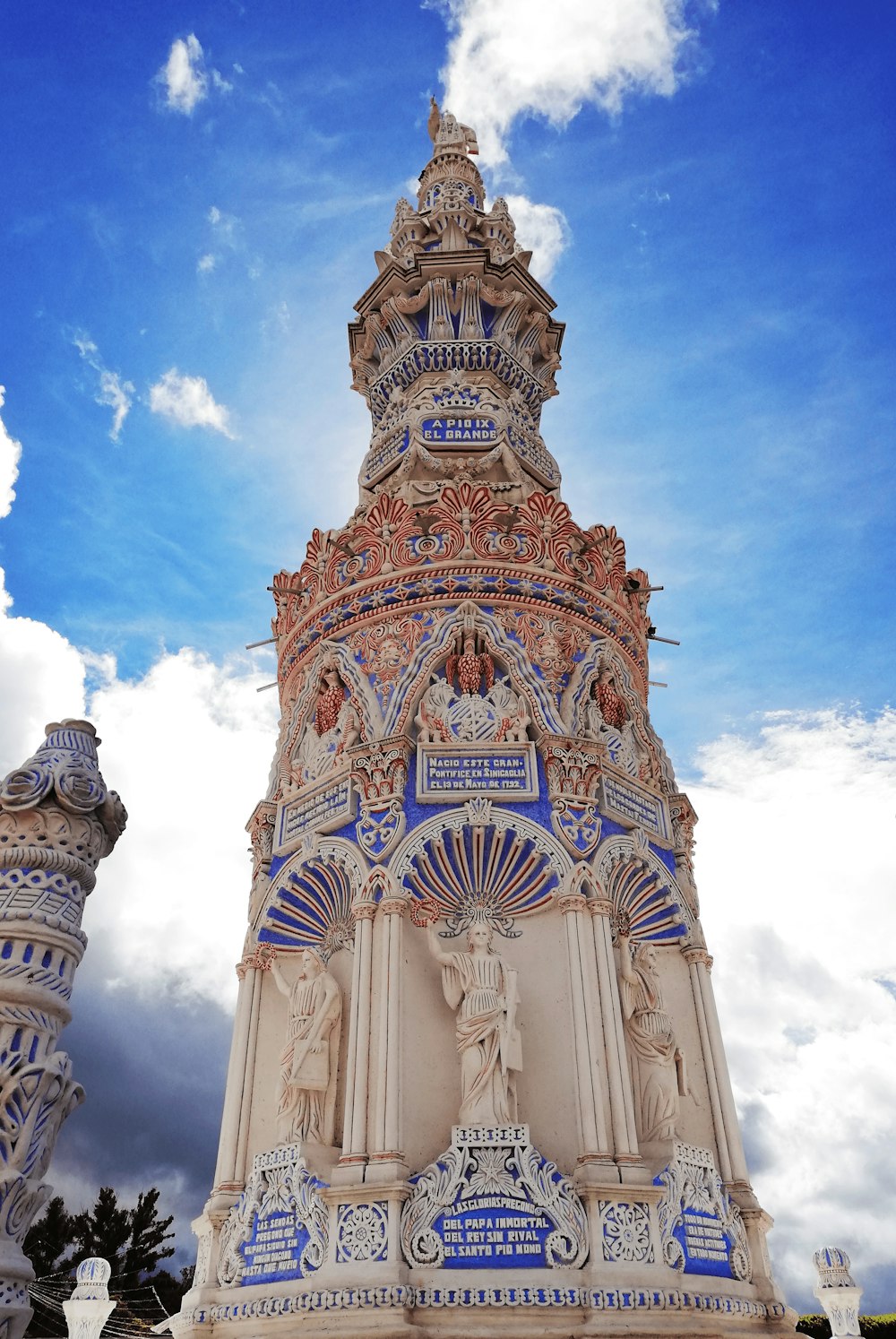 a tall ornate tower with Mission San Miguel Arcángel in the background