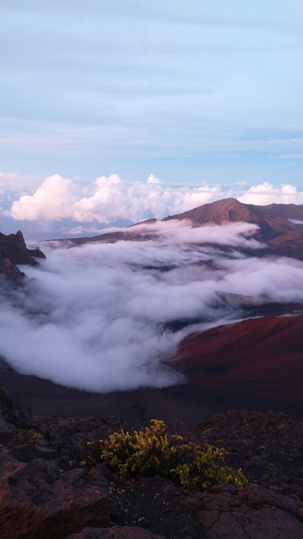 a view of a valley with clouds and mountains in the background