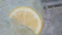 Close-up of a hand holding a frosty classic lemonade with condensation droplets.