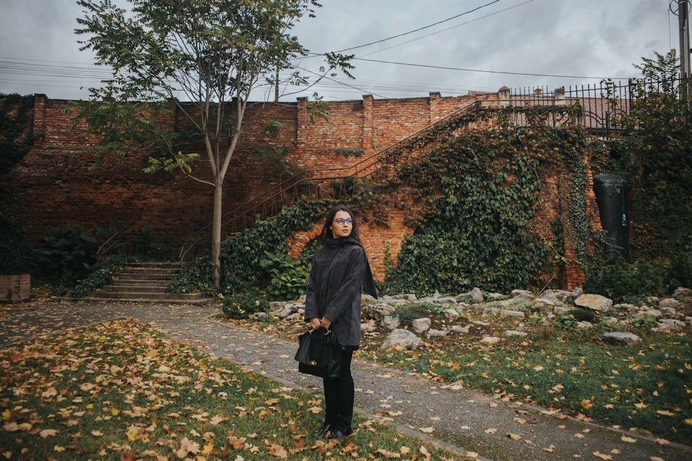 a man standing in front of a brick wall