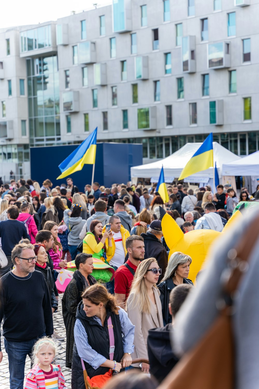 a crowd of people walking on a street with flags