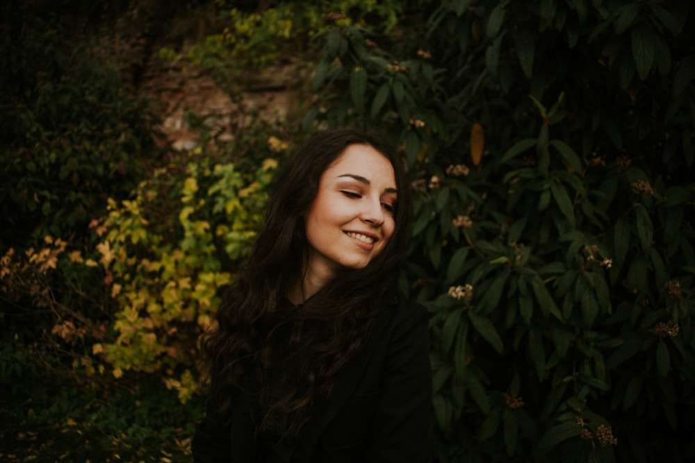 a person smiling in front of a bush