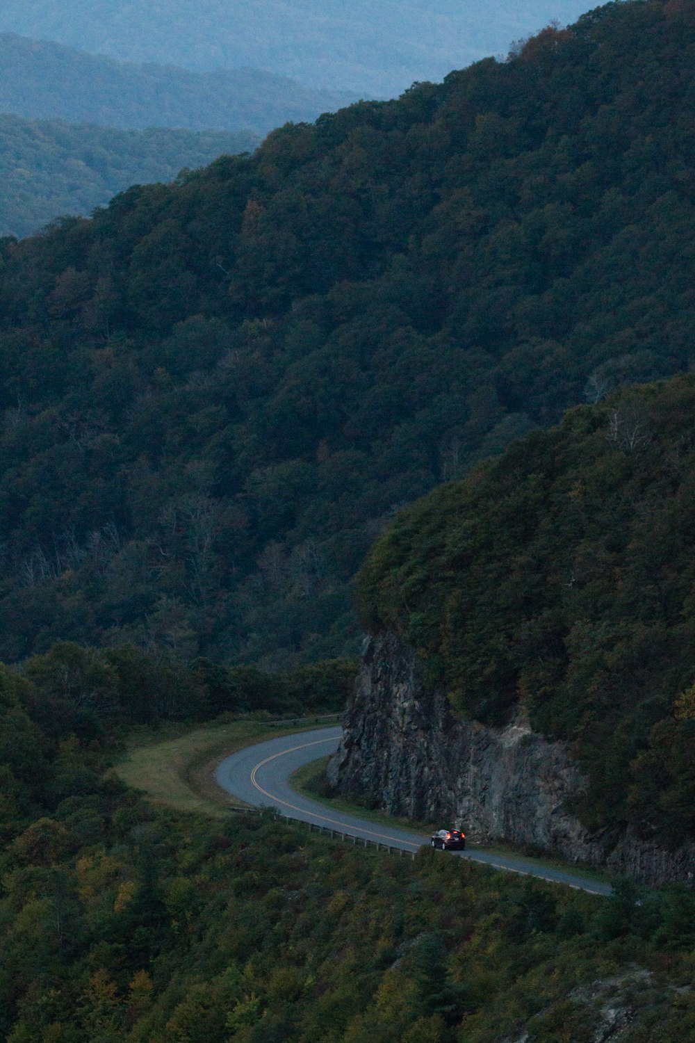 a car driving on a road in a valley between mountains