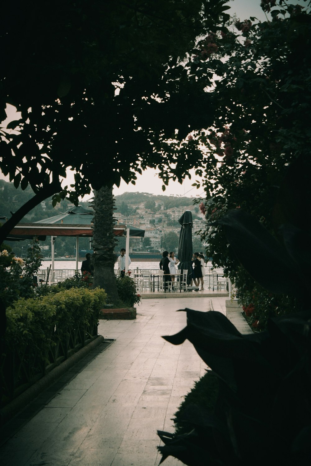 a group of people walking on a path with trees and a building in the background