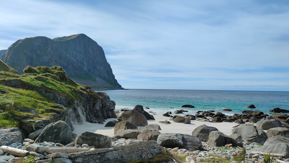 a rocky beach with a body of water in the background