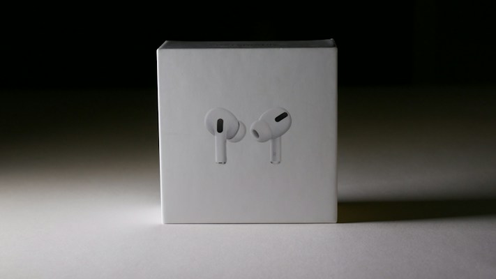 A box featuring a minimalist design with an image of white wireless earbuds on the front, placed against a shadowy background that emphasizes the product.