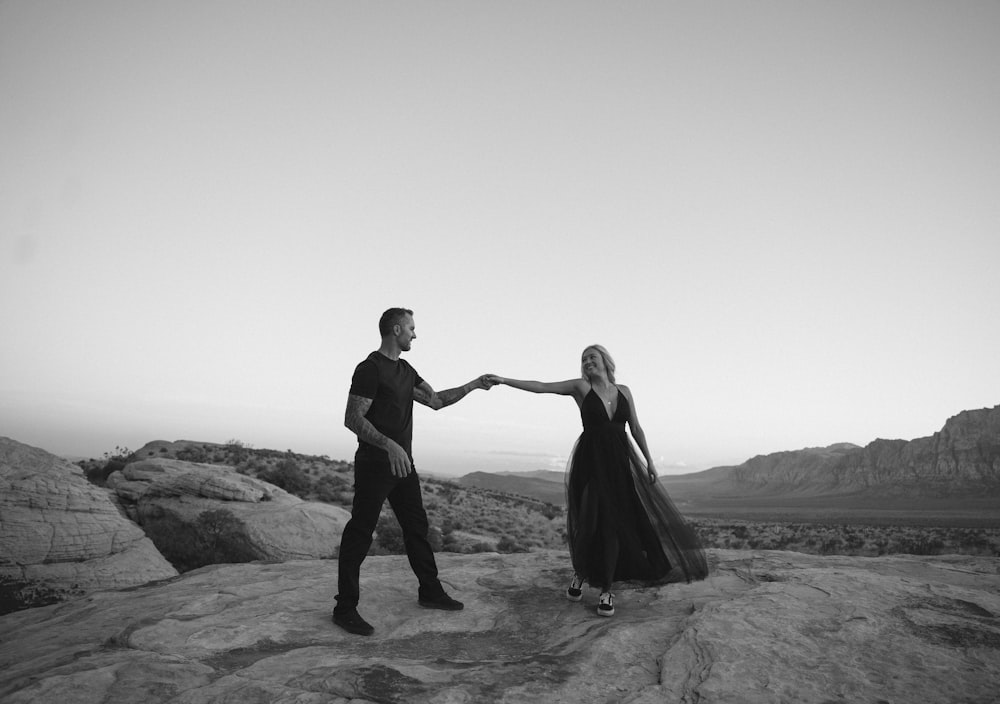 a man and woman dancing on a rocky beach