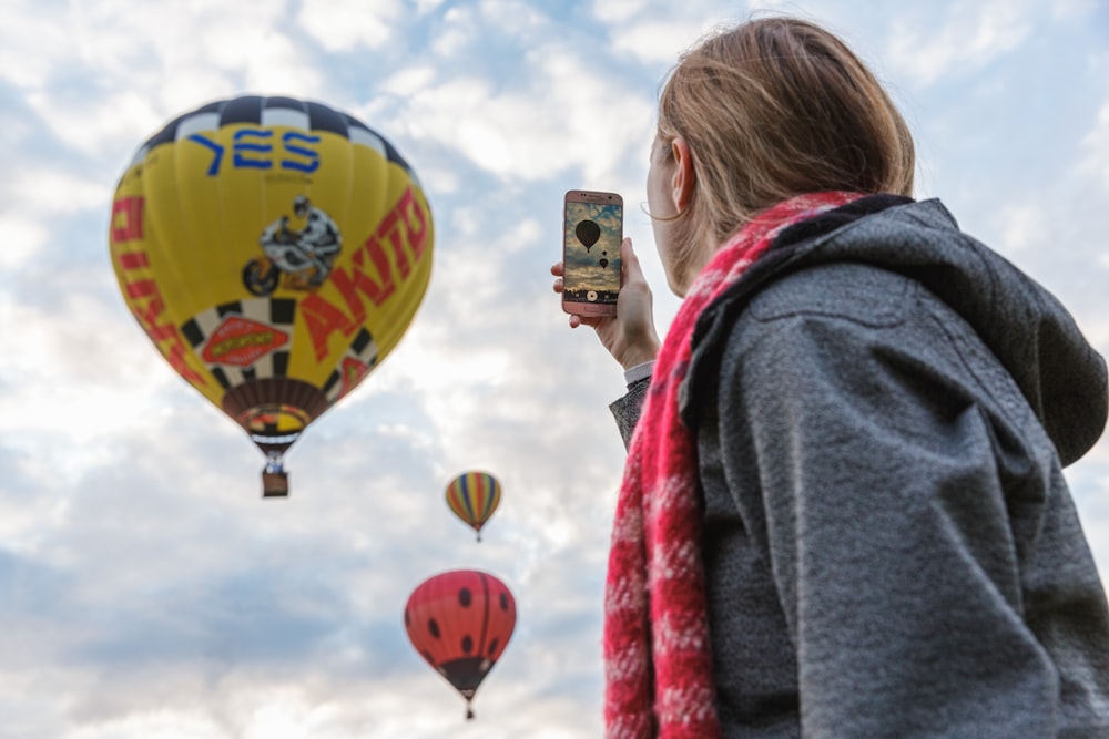 a person taking a picture of hot air balloons