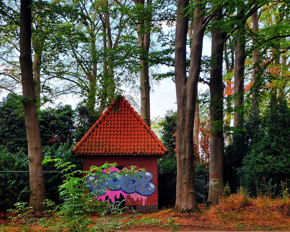 a red building with graffiti in a forest