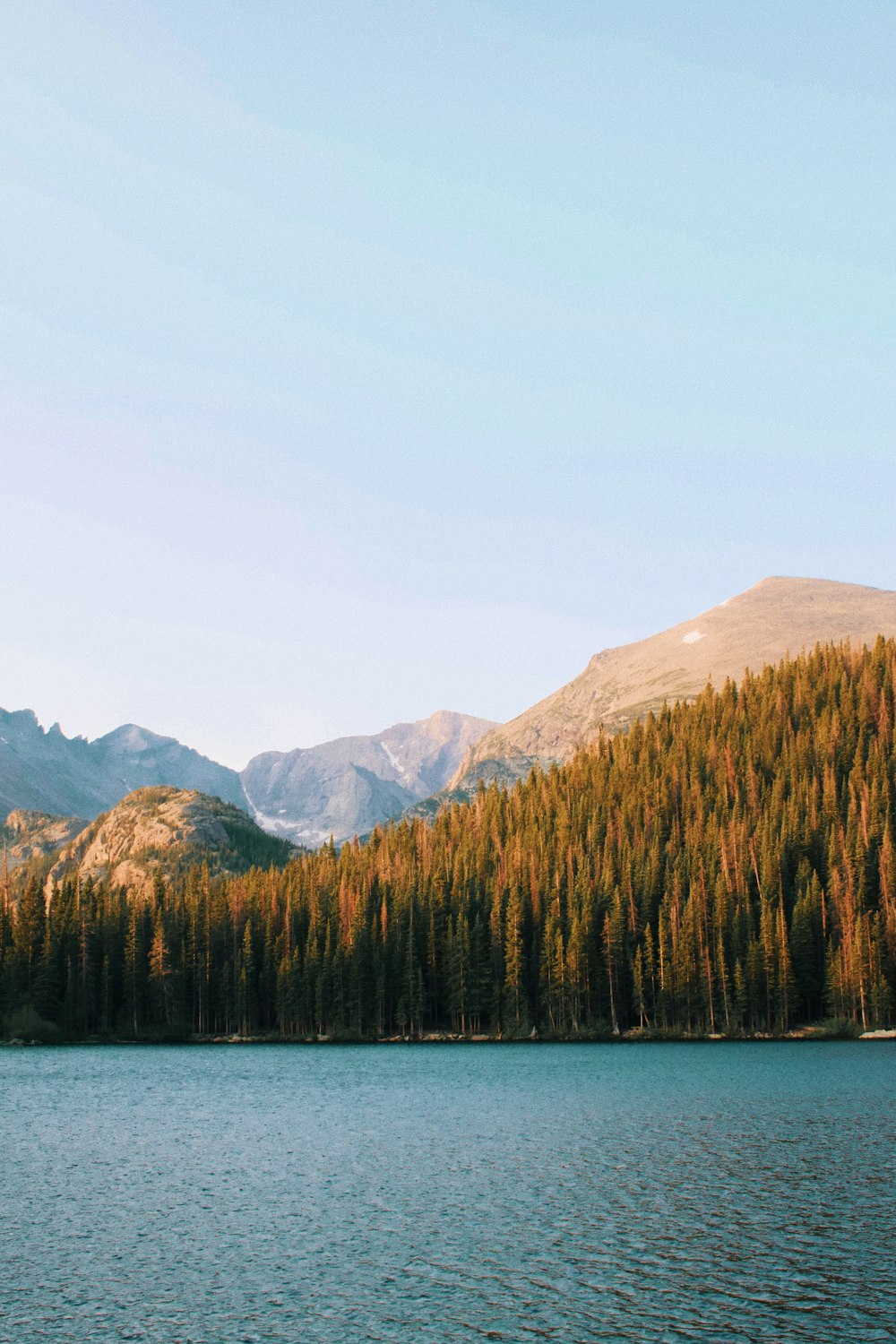 a lake with trees and mountains in the background