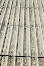 Corrugated metal sheets arranged in parallel rows, showing signs of weathering and rust. The texture is rough and there are visible fasteners at regular intervals.