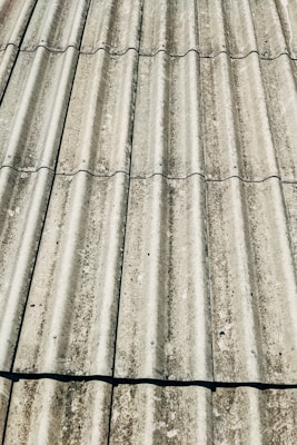 Corrugated metal sheets arranged in parallel rows, showing signs of weathering and rust. The texture is rough and there are visible fasteners at regular intervals.