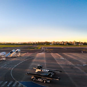 Close-up of engineers applying asphalt rejuvenator on a runway surface at sunrise.