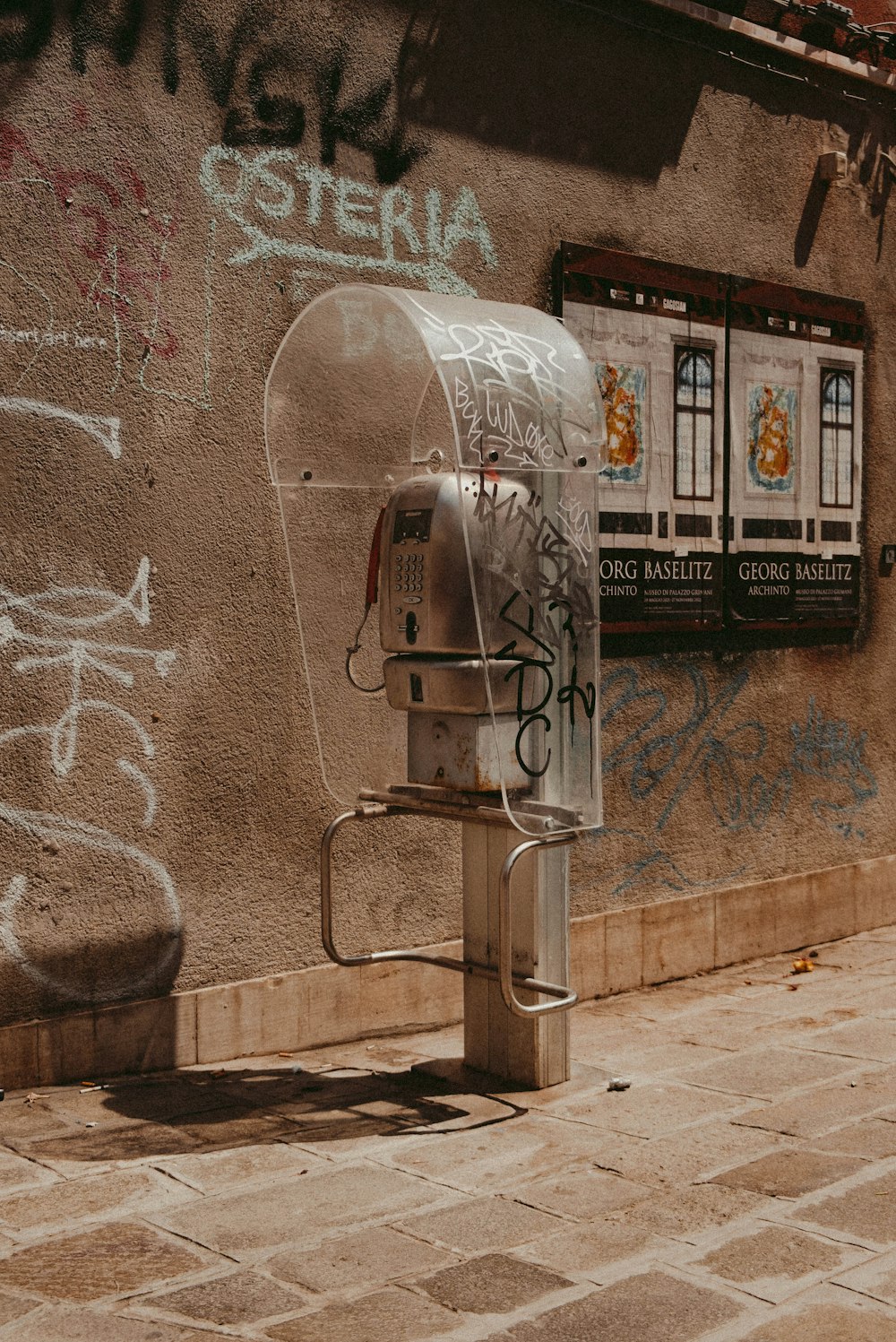 a metal robot in front of a wall with graffiti