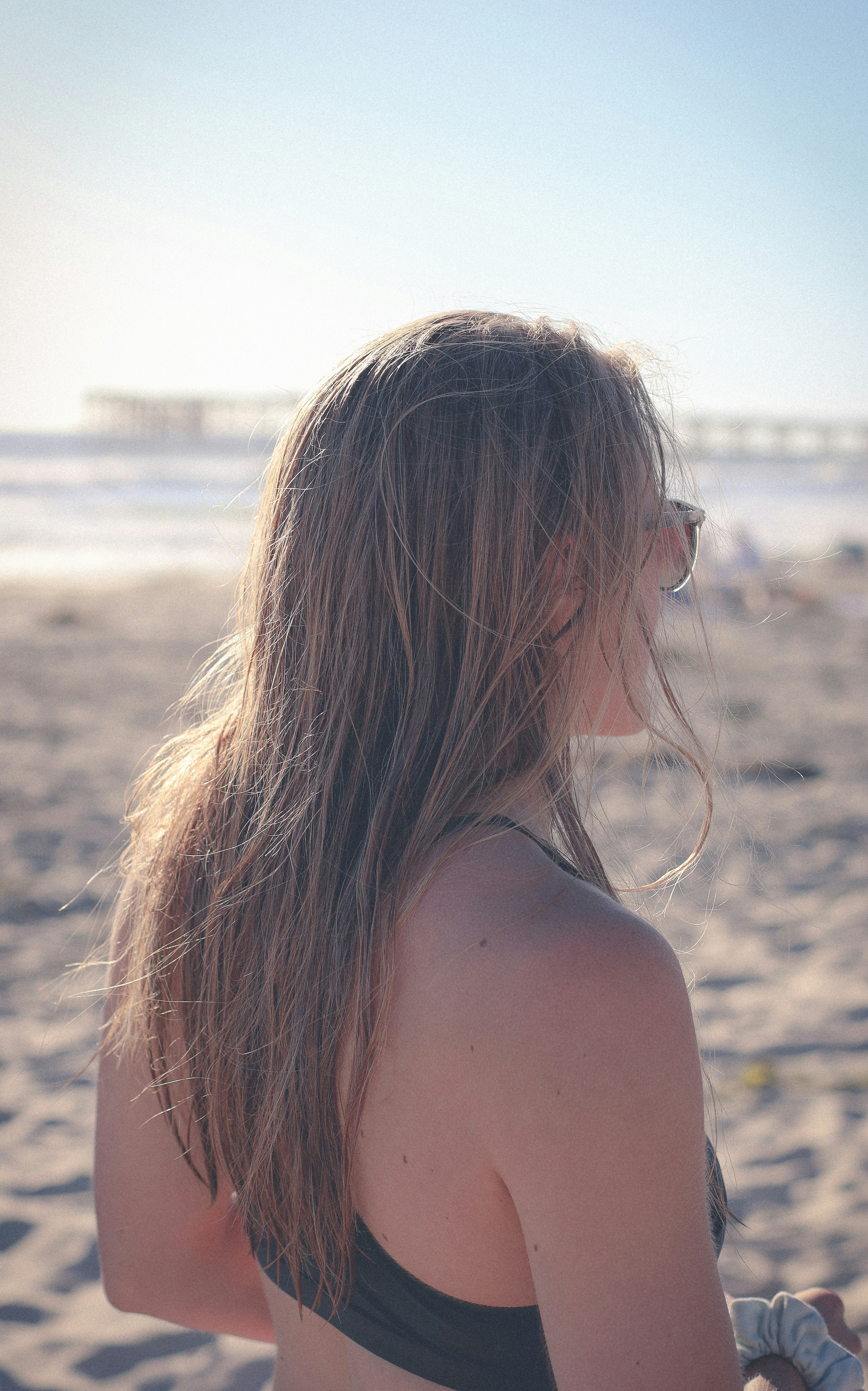 a woman with her hair blowing in the wind on a beach