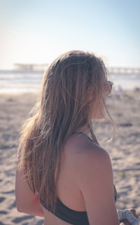 a woman with her hair blowing in the wind on a beach