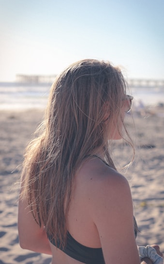 a woman with her hair blowing in the wind on a beach