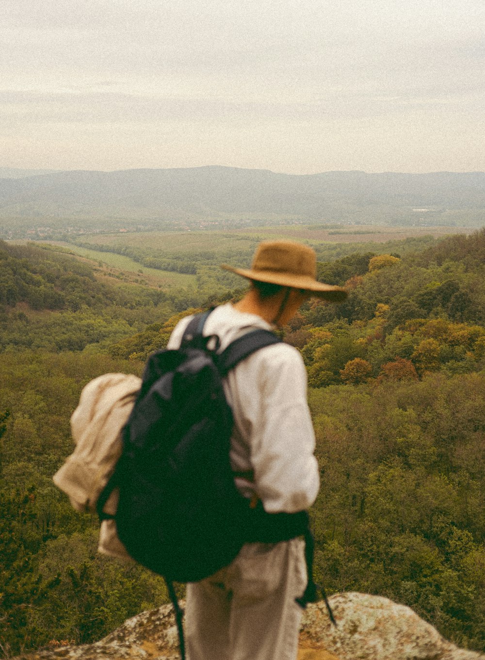 a person with a hat and backpack on a mountain