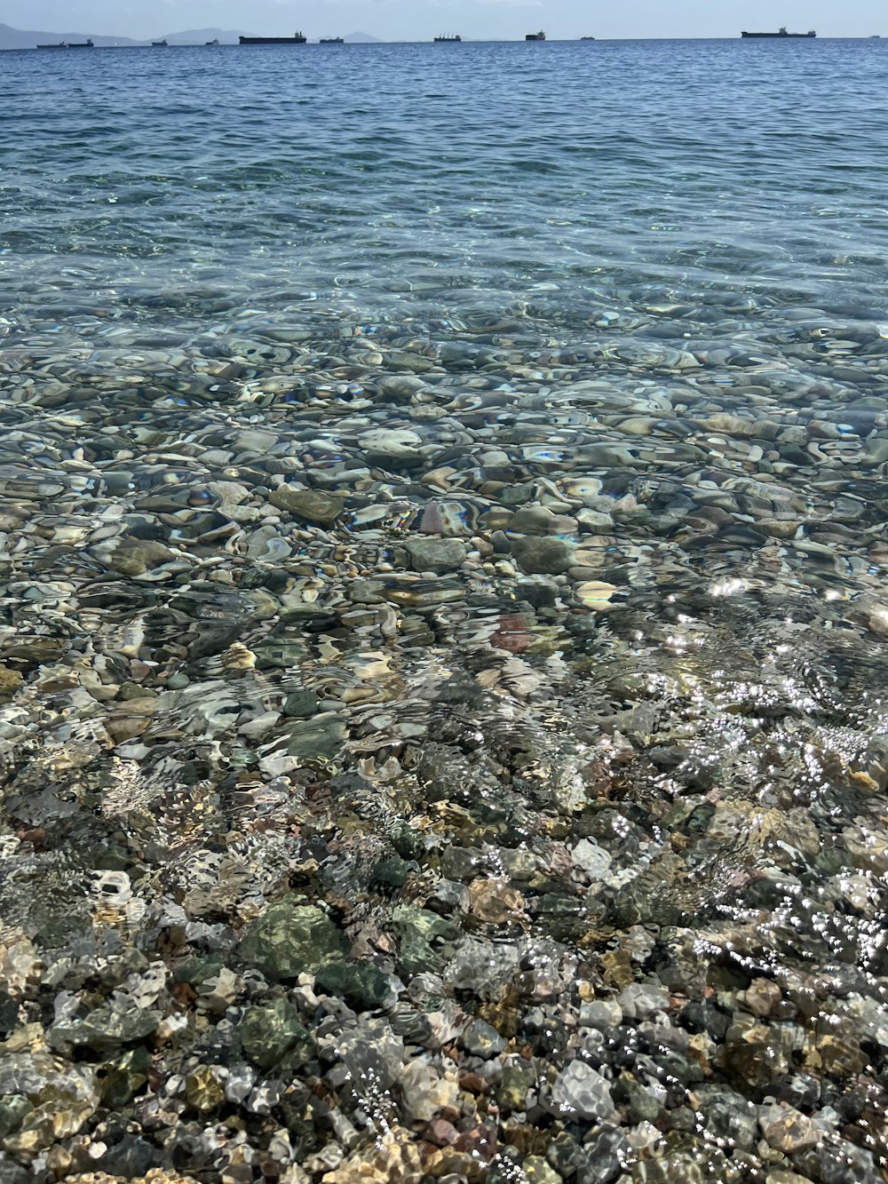 a rocky beach with a body of water in the background