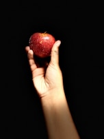 A close-up of a hand holding a glowing apple.